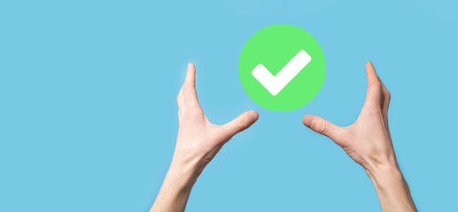 Hand holds green icon Check mark,Check Mark Sign, Tick Icon,right sign,circle green checkmark button,Done.On dark background.Banner.Copy space.Place for text.
