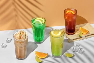 beautiful still life composition with four transparent glasses of summer drink. green lemonade with lime, mint, lemon and citrus on a tropical background with shadows of a palm tree
