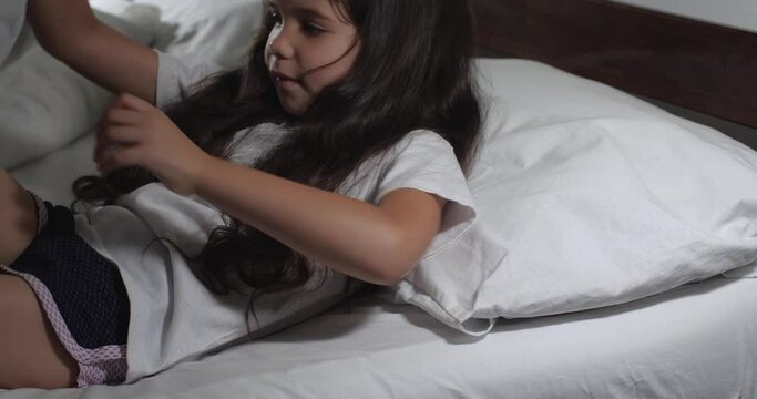 Close up  of little girl 6 years old with long brown hair falling asleep  in bed with white linens in light room. Childish fears and nightmares.  Preschool girl  going to bed. Good night concept 4k 