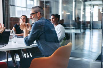 Happy mature businessman attending a meeting with his team