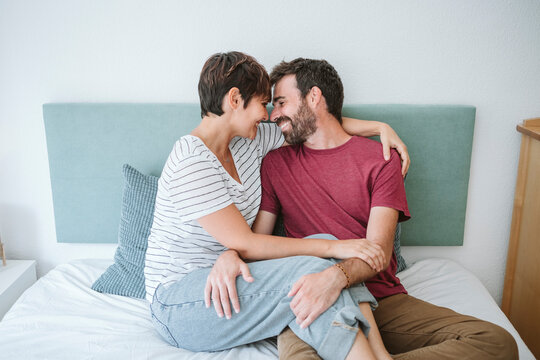 Romantic couple sitting together on bed at home