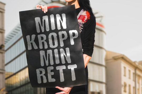 The phrase " Min kropp min rett " on a banner in women's hand. Woman holds a black cardboard with an inscription. Human rights. Equality. Gender. Protest. Law. Legal. Help. Fight. Freedom