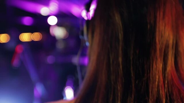 Back view of a girl dj in a nightclub