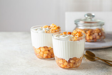 Caramelized cinnamon apple with greek yogurt and walnuts, dessert on white table.