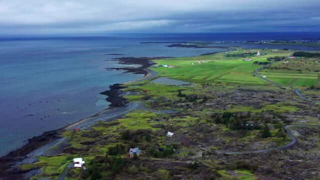 Panorama Of The Rugged Landscape Of Gardabaer Town With A Distant View Of Garoakirkjugarour Cemetery In Reykjavik, Iceland. aerial
