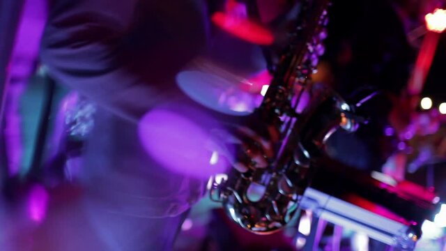 Saxophonist playing on stage, blurred festive picture
