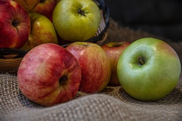 ripe juicy red and green apples grown in a personal garden in a basket on burlap cloth close up