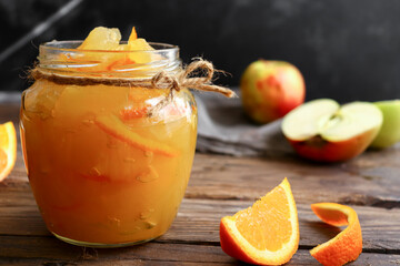 Apple jam in a transparent glass jar. Jam from apples and orange on a light background. Delicious...