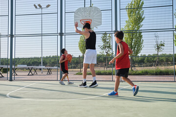 Basketball trainer play basketball with two children, one has a leg prosthesis.