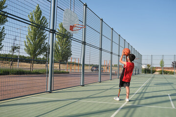Basketball kid player with a leg prosthesis throwing the ball to the basket.