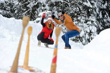 Cheerful man and woman cheering on snow during vacations