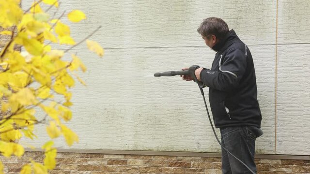 Man cleaning walls with high pressure power washer. Washing cladding walls house. High quality 4k footage
