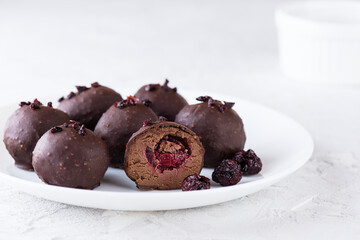 Chocolate truffles with cherry filling in cognac on a white plate. Sugar, gluten and lactose free and vegan.