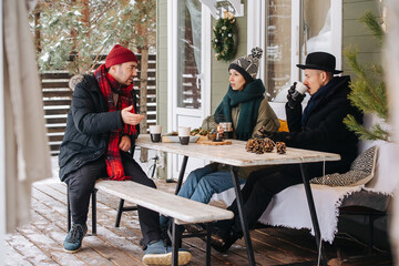 Talking, serious faced friends sitting on a snowy terrace, drinking coffee