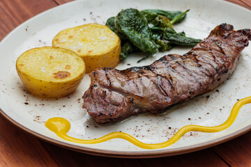 Delicious fried juicy beef on a plate with potatoes and green peppers