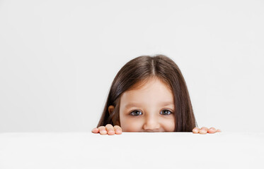 One cute beautiful little girl playing isolated on white studio background. Human emotions, facial expression concept.