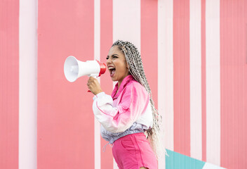 Young woman screaming through megaphone by wall