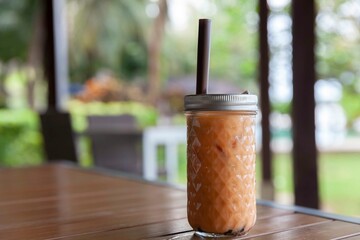 Thai tea with milk in a glass jar placed on a wooden table