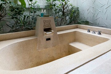 A large brown stone bathtub in a luxurious bathroom