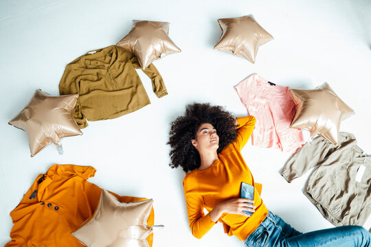 Young woman amidst balloons and clothes lying on floor