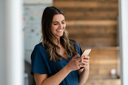 Smiling businesswoman using mobile phone in office
