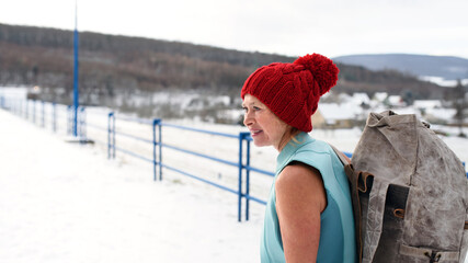 Active senior woman in swimsuit with backpack outdoors in winter, cold therapy concept.