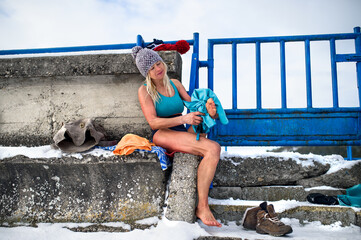 Active senior woman in wet swimsuit drying feet with towel outdoors in winter, cold therapy concept.