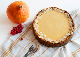 Autumn pumpkin pie on a light background with decorative pumpkin