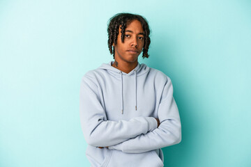 Young african american man isolated on blue background suspicious, uncertain, examining you.