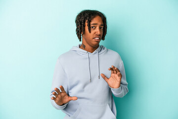 Young african american man isolated on blue background rejecting someone showing a gesture of...