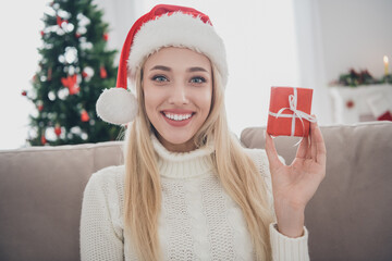 Photo portrait smiling woman sitting on sofa wearing white knitted sweater headwear keeping tiny...