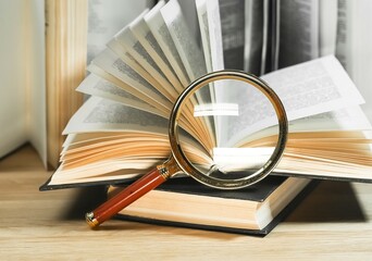 Magnifiers and books with turning pages on wood table. Reading and knowledge concept.