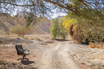 Mess in nature. Environmental pollution by people. Abandoned chair along the dirty road, separate chair beside the dusty road.