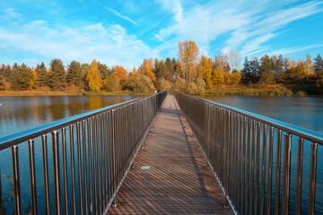 A bridge leading to the center of the lake above the water with metal railings on the background 