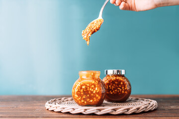 Two jars of caramel with nuts on wooden background.