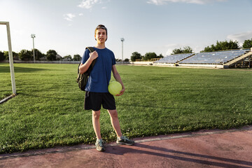 concept of sports and health - teen boy posing at a stadium, a soccer field with green grass.