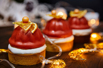 Christmas cakes made from sand tartlets, raspberry confit, and Mascarpone mousse on a background of glowing garlands