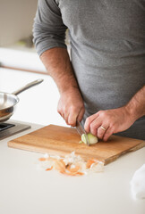 Obraz na płótnie Canvas Man cutting vegetables on wooden desk in home kitchen