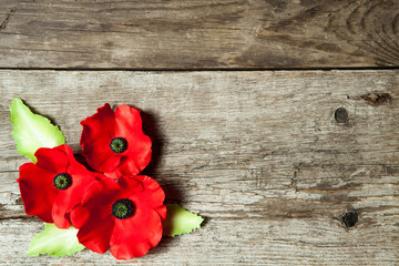Fototapeta na wymiar Poppy pin for Remembrance Day. Backed on old beautiful high grain, detailed wood.