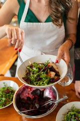 Obraz na płótnie Canvas Chef's hands and dish. The chef serves a plate of salad. Beetroot, arugula, vinaigrette sauce. Food preparation technique.