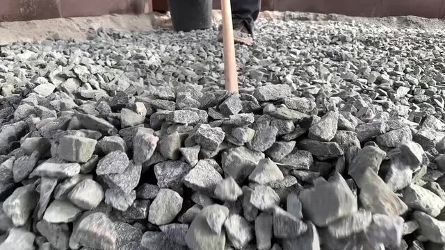 Raking the gravel into the areas to try and even it out at the start of the hardscaping. Closeup of gravel work for landscaping and hardscaping slow motion