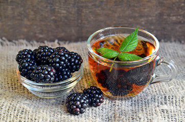 Blackberry tea with fresh picked blackberries in a glass cup on a burlap cloth background.Healthy drink,diet,alternative therapy or herbal medicine concept.