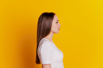 Profile side photo of young girl calm serious look empty space wear casual white t-shirt isolated over yellow background