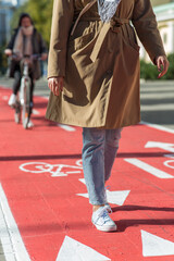 city and traffic concept - close up of woman walking along separate bike lane or red road with...