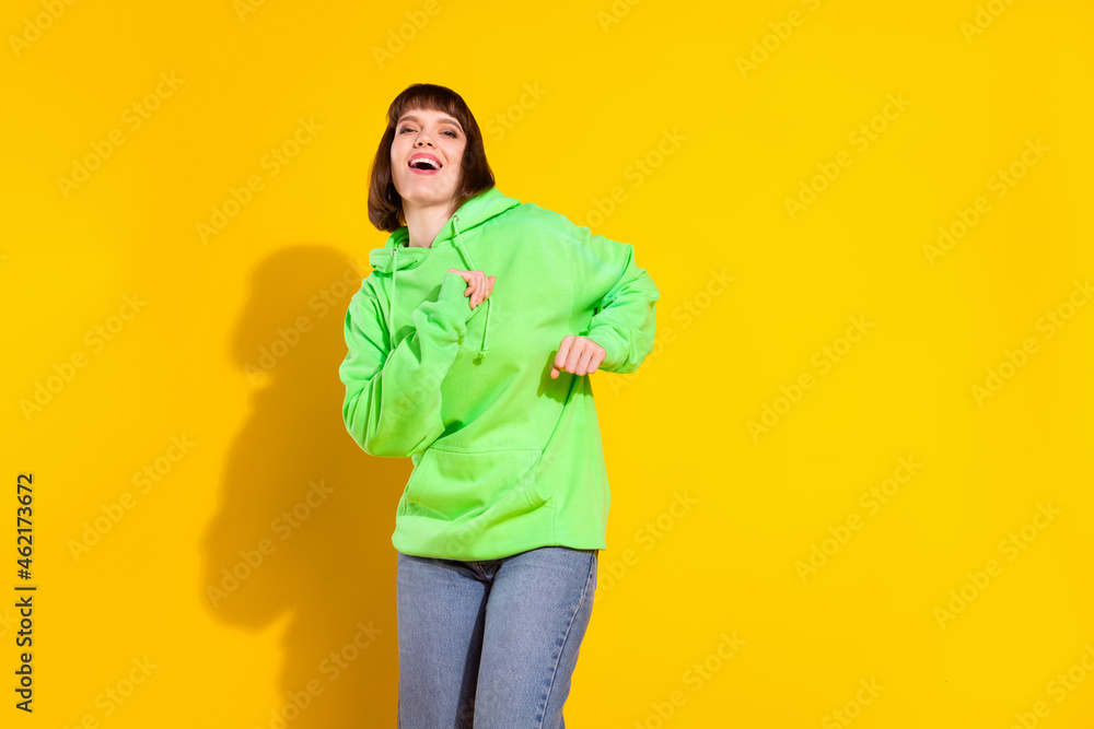 Poster Portrait of attractive cheerful girl dancing enjoying free spare time isolated over bright yellow color background