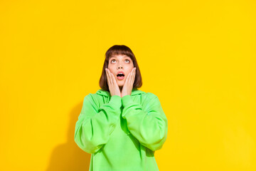 Portrait of attractive amazed girl looking up copy empty blank space isolated over bright yellow color background