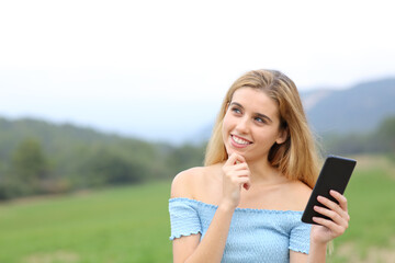 Happy teen holding phone and wondering outdoors