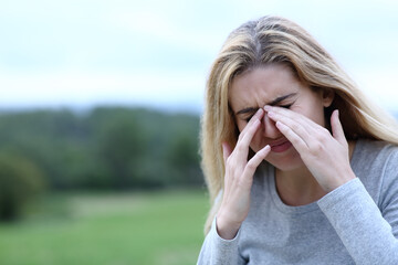 Teen scratching itchy eyes outdoors
