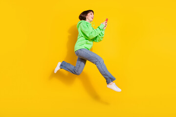 Fototapeta na wymiar Full body photo of charming happy nice young woman jump up look hold phone isolated on yellow color background