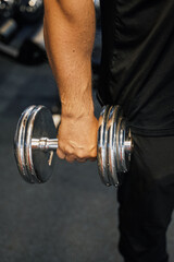 Fototapeta na wymiar a man's hand holds a dumbbell in the gym